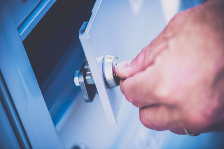 A hand unlocking a safe deposit box. 