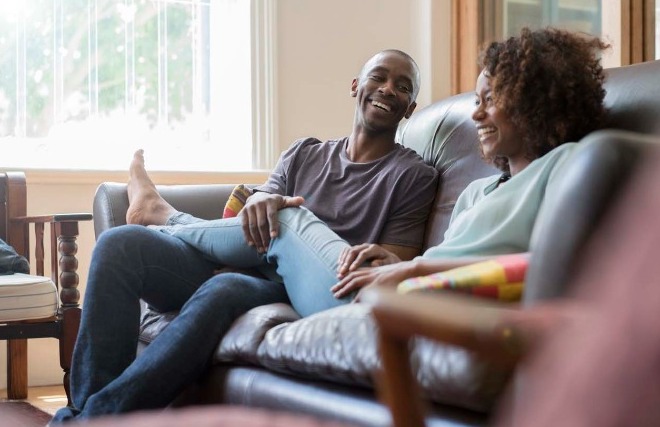 A couple on the couch smiling with each other.