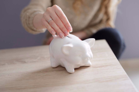 A woman putting change into a piggy bank.