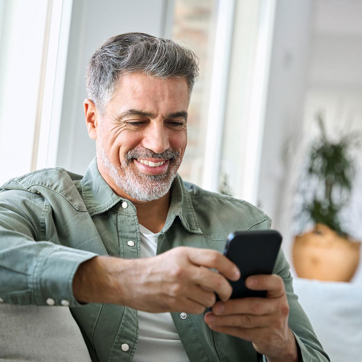 Grey haired man using phone at home