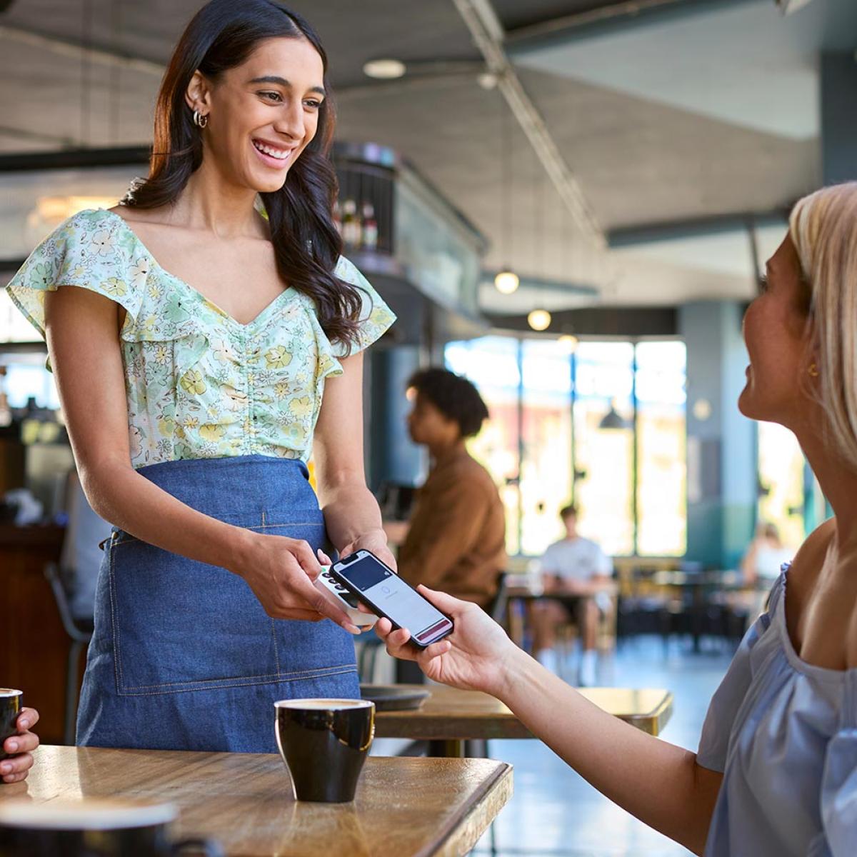 Woman using tap-to-pay at a cafe