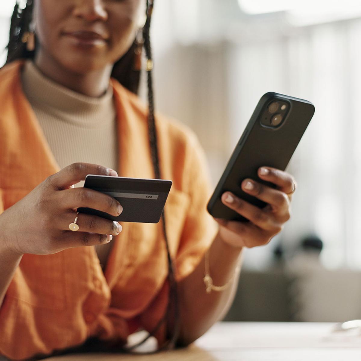woman using phone and looking at credit card