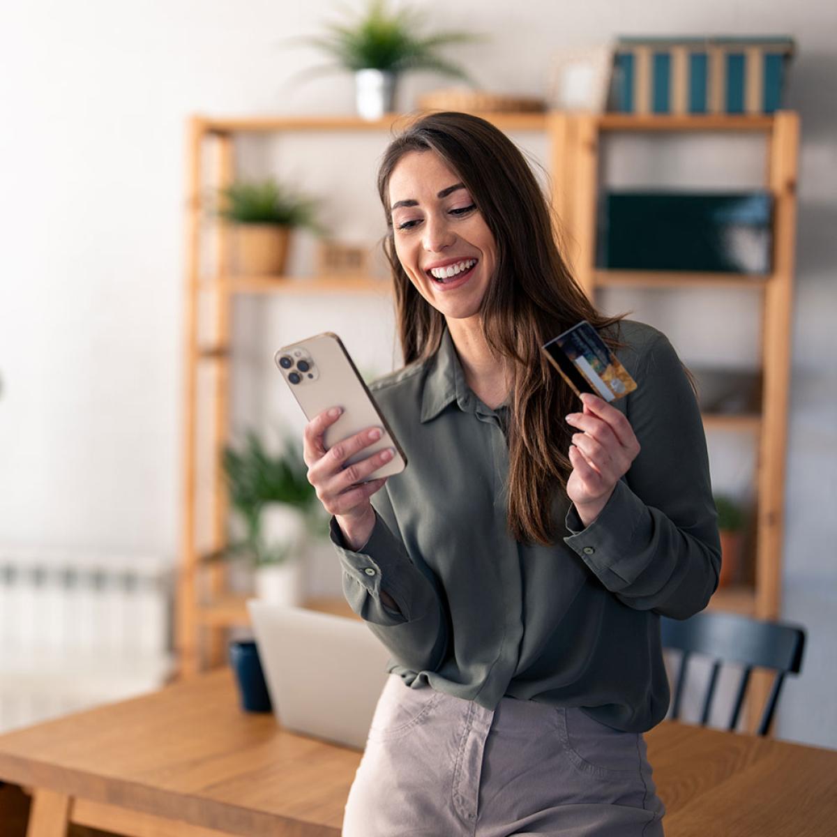 smiling woman holding credit card and phone