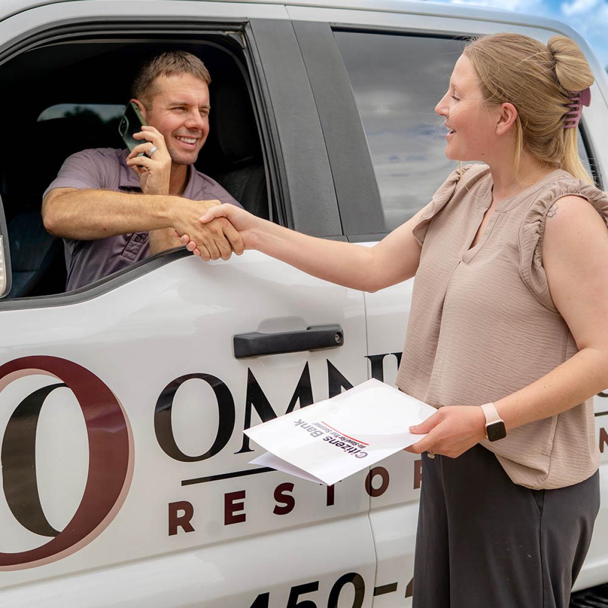 bank employee shaking hands with business owner in truck