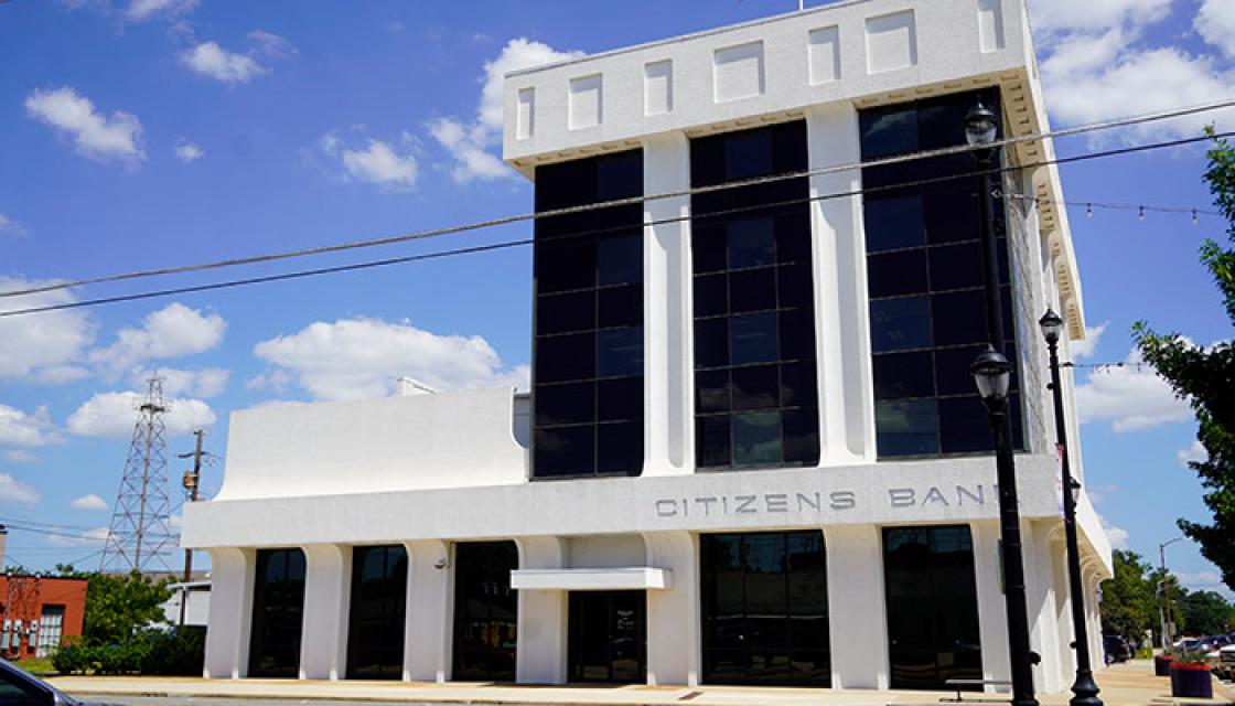 Four story white building with large black glass windows
